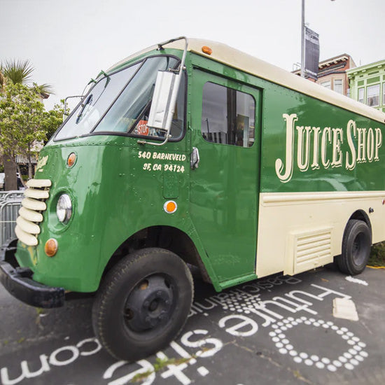 Vintage green and cream Juice Shop truck parked on city street.