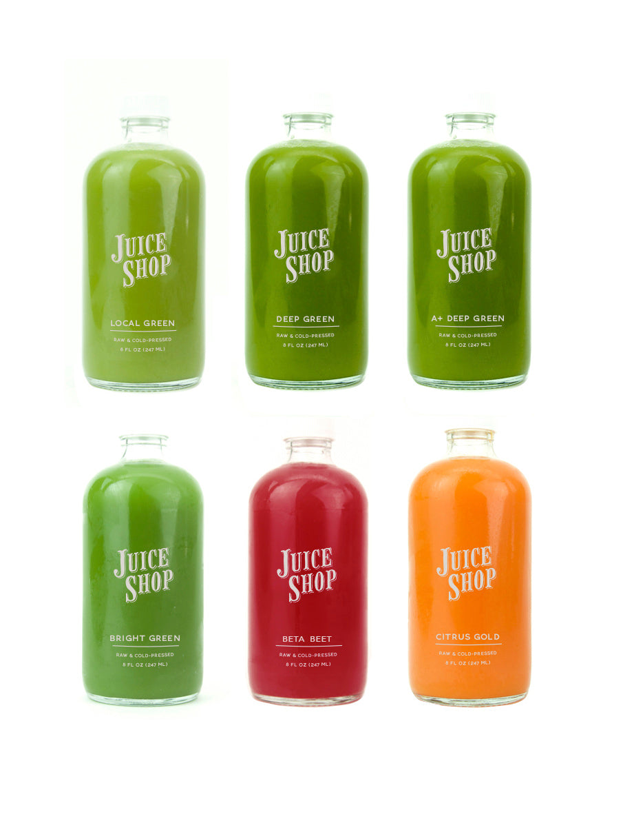Juice Shop raw cold-pressed juices in glass bottles, featuring green, red, and orange varieties.